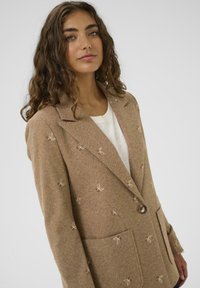 Bruine herringbone blazer met geborduurde vlinder motieven, met notch revers, een enkele knoopsluiting en twee voorkruiszakken.