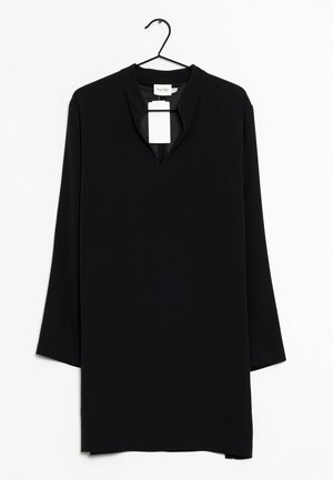 Czarna tunika z długim rękawem, z wycięciem przy dekolcie, gładką fakturą i przymocowaną metką. Zawieśnięta na czarnym haczyku na białym tle.