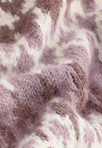 Vilnas sega ar dažādām tekstūrām siltos mauve, krēmkrāsas un brūnos toņos, ar mīkstu, pūkainu virsmu un svītraina raksta dizainu.