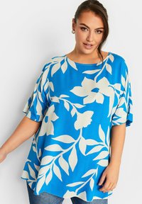 Top floreale blu con maniche corte oversized, caratterizzato da motivi di foglie e fiori bianchi, tessuto morbido e fit rilassato.