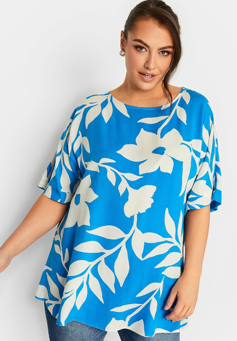 Top floreale blu con maniche corte oversized, caratterizzato da motivi di foglie e fiori bianchi, tessuto morbido e fit rilassato.