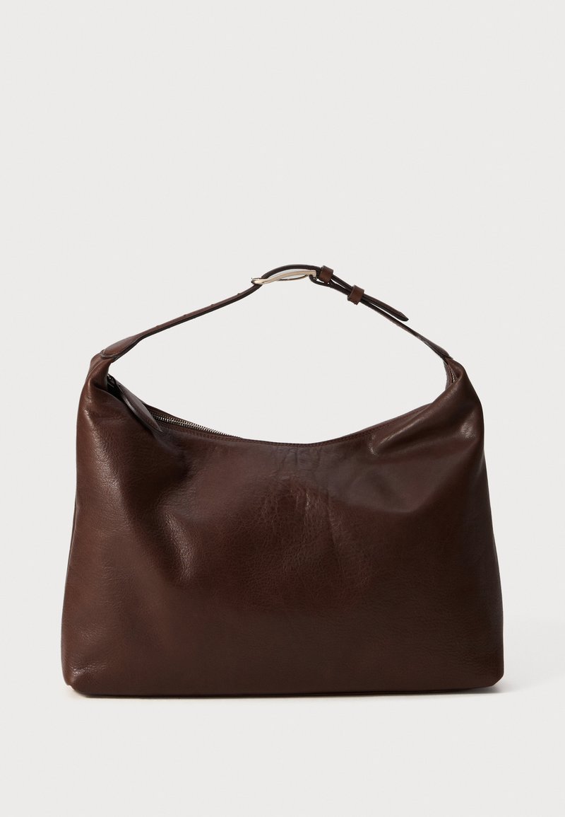 Ciemnobrązowa, miękka skórzana torba na ramię z regulowanym paskiem i górnym zamknięciem na zamek, na jednolitym jasnym tle.