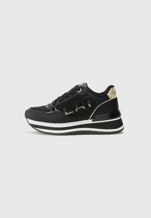 Svart sneaker med nät- och syntetmaterial, reflekterande design, guldaccenter på hälen och en vit randig mellansula.