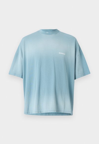 Ανοιχτού μπλε oversized t-shirt με απαλό υλικό, στρογγυλή λαιμόκοψη και κοντά μανίκια. Διαθέτει ένα ασθενές λογότυπο "BONSAI" τυπωμένο στο στήθος.
