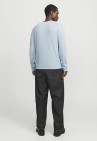 Suéter de punto azul claro con cuello redondo, combinado con pantalones de mezclilla oscuros. El suéter tiene un acabado texturizado y un corte relajado.