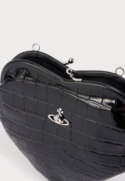 Μαύρη τσάντα χειρός με ανάγλυφη υφή κροκοδείλου σε σχήμα καρδιάς, γυαλιστερό φινίρισμα, ασημένιο κούμπωμα και λείο εσωτερικό επένδυση.