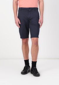 Marine cargo shorts lavet af letvægtsstof, med sidelommer og knælang skæring. Parret med sorte sneakers og sorte sokker.