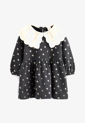 Vestito nero con stampa floreale bianca, maniche a palloncino e colletto avorio a scallop. Design della gonna arricciata. Tessuto morbido.