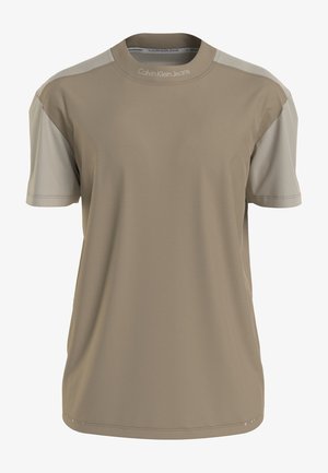 Beżowy t-shirt z krótkim rękawem, jasnoszarymi rękawami, okrągłym dekoltem i napisem „"Calvin Klein Jeans"” na kołnierzyku. Brak widocznych grafik lub wzorów.