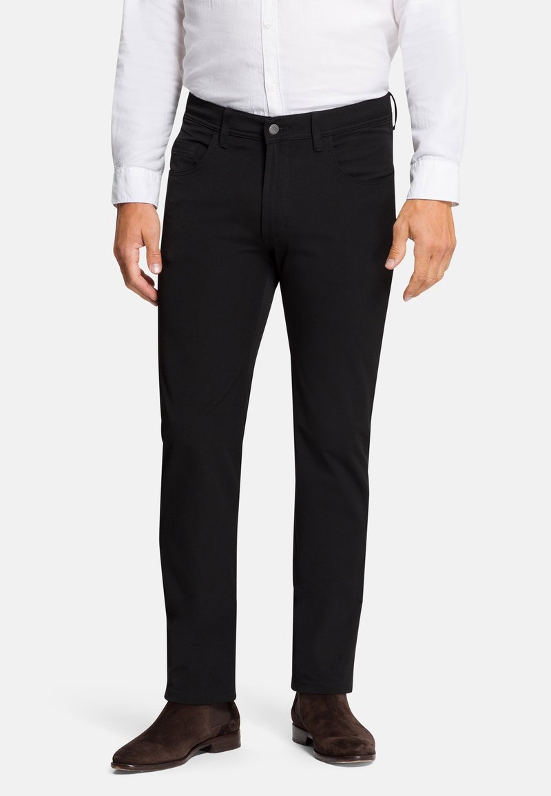 Černé slim-fit kalhoty vyrobené z měkké tkaniny, s několika kapsami a hladkým povrchem. Doplněné hnědými semišovými kotníkovými botami.