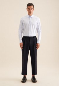 Camicia azzurra chiara con maniche lunghe, abbinata a pantaloni neri a pieghe e scarpe di pelle nera. Design semplice e sartoriale.