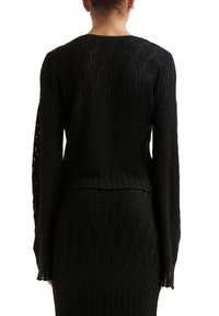 Schwarzer Strickpullover mit strukturiertem Rautenmuster, langen Ärmeln und cropped Saum, der ein nahtloses Design auf der Rückseite zeigt.