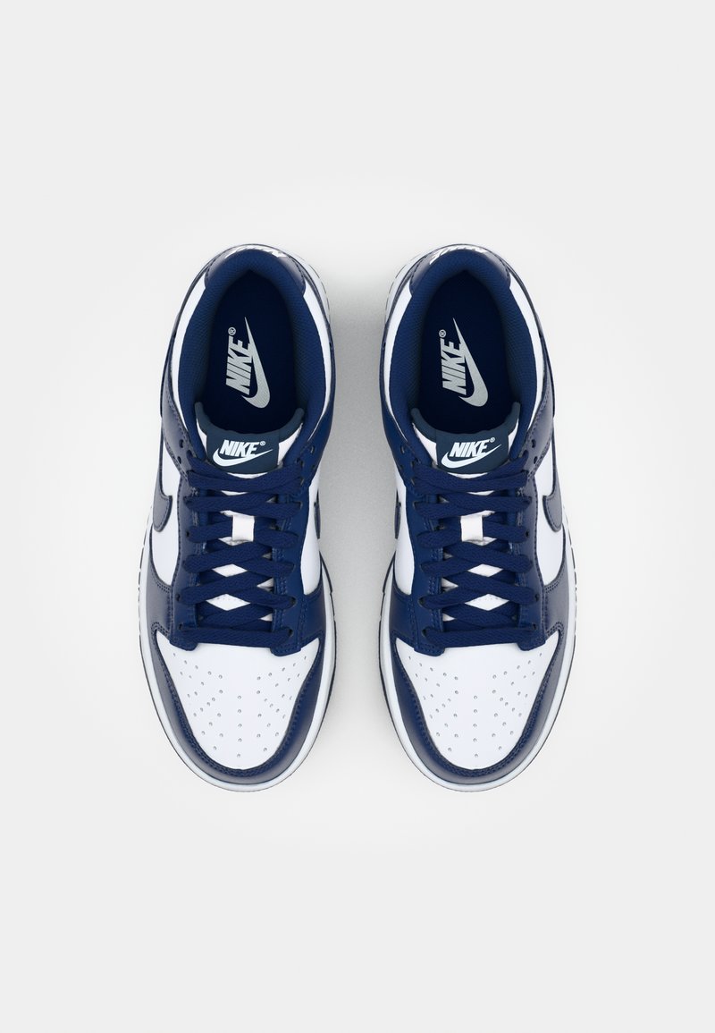 Sneaker in pelle di colore blu navy e bianco con punta perforata, lacci e un logo Nike prominente sulla linguetta e sul lato.