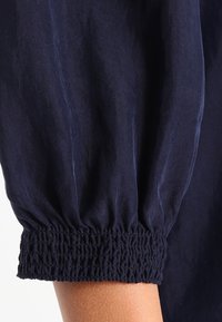Navy blue puff sleeve fabric with a gathered elastic cuff, featuring a soft, textured finish and subtle sheen.