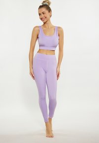 Set de sport din paiete lila, format din sutien sport și leggings cu talie înaltă, realizat dintr-un material neted și elastic. Include bretele late și un design care se mulează pe corp.