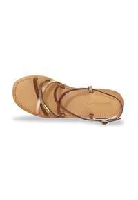 Sandal de cuero con plantilla beige y correas marrones. Presenta un diseño delgado entrecruzado con un acento metálico y costura a lo largo de los bordes.