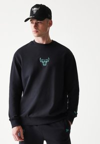 Μαύρο φούτερ από βαμβάκι με στρογγυλή λαιμόκοψη, με κεντητό ταυράκι σε τιρκουάζ στο στήθος. Συνδυάζεται με παντελόνι στο ίδιο χρώμα.