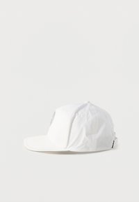 Λευκό καπέλο με καμπύλη γείσο, που διαθέτει πλαϊνή ετικέτα με λογότυπο, κατασκευασμένο από ελαφρύ υλικό με λείο υφή.