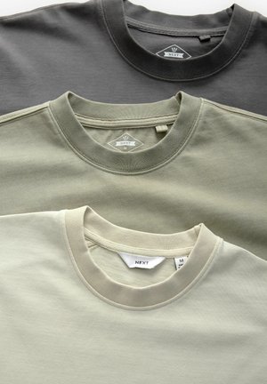 Drie crewneck t-shirts in donkergrijs, olijfgroen en lichtbeige. Gemaakt van zachte katoen, met ribgebreide halslijnen en labeltags.