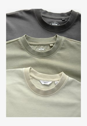 Trois t-shirts à col rond en gris foncé, vert olive et beige clair. Fabriqués en coton doux, avec des colliers côtelés et des étiquettes.
