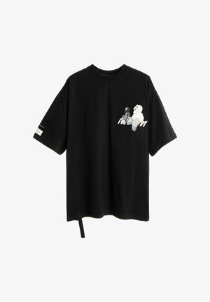 Camiseta negra de gran tamaño hecha de algodón, con un estampado en el bolsillo de dos figuras de dibujos animados. Incluye una correa lateral y mangas cortas.