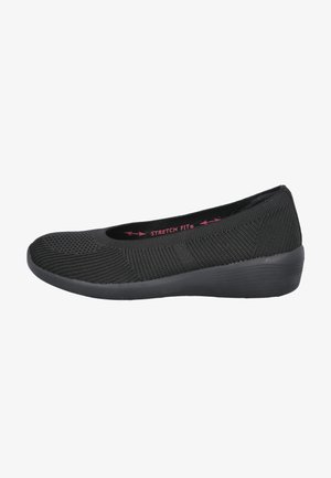Zapato sin cordones para mujer negro con parte superior tejida, suela flexible, tacón bajo en cuña y texto "Stretch Fit" en el interior.