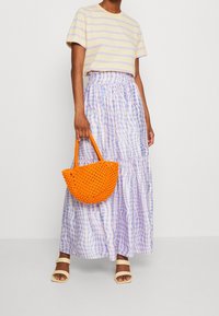 Striped yellow and purple t-shirt paired with a tiered lavender and white gingham skirt. Orange woven handbag and cream strappy sandals.