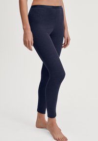 Donkerblauwe legging gemaakt van zachte stof met een gladde textuur. Ze hebben een aansluitende pasvorm en een simpele, elastische tailleband.