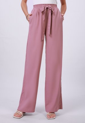 Pantalons larges rose pâle en tissu lisse avec une taille élastique et un nœud à l'avant. Comprend des poches des deux côtés.