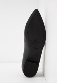 Sorte læder højhælede sko med spidse tæer og en glat overflade. Har en tekstureret gummisål for godt greb. Logo trykt på siden.