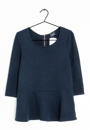 Haut à manches longues bleu marine avec un motif en nid d'abeille texturé, encolure dégagée et ourlet évasé. Présente une fermeture éclair au dos apparente.