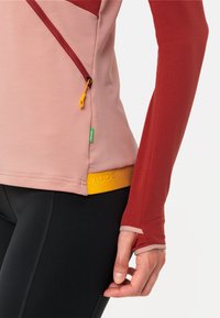 Langärmliges Sportoberteil in Hellrosa und Rot mit einem orangefarbenen Reißverschluss-Zug, gelbem Bund und Daumenlöchern an den Bündchen.