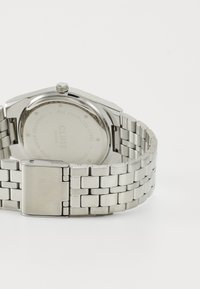 Orologio in acciaio inossidabile di colore argento, con una cassa rettangolare e un bracciale a maglie, che presenta una finitura lucida e un retro inciso.