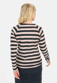 Langekleurige top met marineblauwe en lichtroze horizontale strepen, ronde halslijn en zachte stof, gecombineerd met een donkere rok.