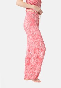 Lätta, korallfärgade pyjamasbyxor med blommönster, vida ben, elastisk midja och dragsko. Tyget har en mjuk och slät textur.