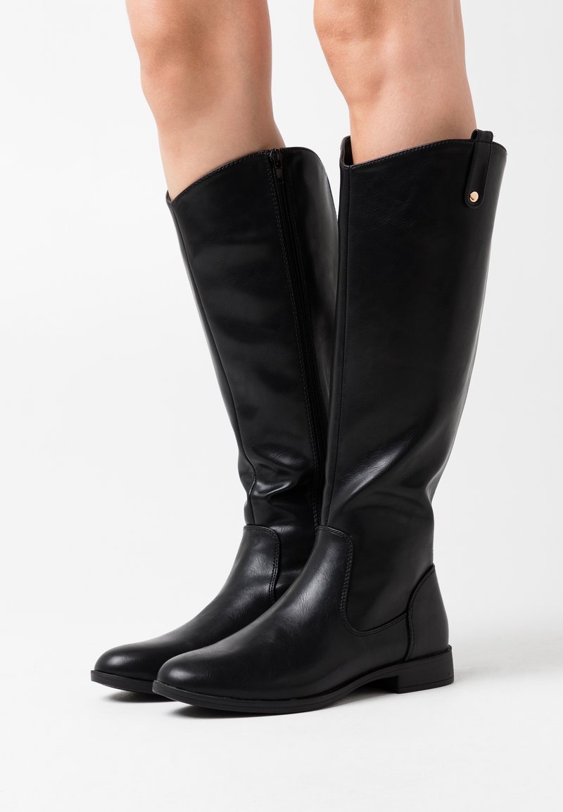 Bottes noires en cuir hautes jusqu'au genou avec une texture lisse et une semelle plate. Elles possèdent une fermeture éclair sur le côté et un petit accent en rose doré.