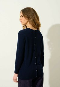 Granatowy sweter wykonany z miękkiego materiału, z długimi rękawami, okrągłym dekoltem i detalem z zapięciem na guziki z tyłu.