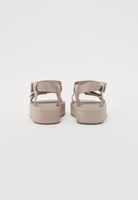 Flate sandaler med plattformsåle i lys beige; har tekstilstropper og en teksturert såle. Åpen bakdesign med justerbare stropper.