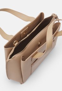 Beige leather handbag with textured exterior, dual top handles, and gold-tone hardware. Features a zip closure and multiple compartments.