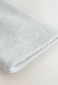 Jasnoszara tkanina złożona w fałdy, o miękkiej teksturze, z starannie przeszytymi brzegami. Materiał wygląda jak polar, gładki z delikatnym połyskiem.