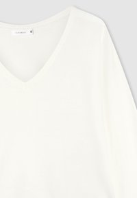 Maglione bianco a maniche lunghe, con scollatura a V, realizzato in tessuto morbido e con collo a costine. L'etichetta riporta "Terranova", taglia S. Texture liscia, design minimale.