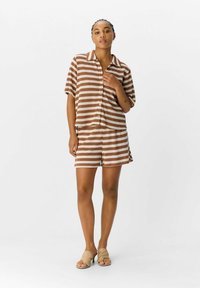 Bruine en beige gestreepte korteblauwe shirt met korte mouwen en bijpassende shorts, gemaakt van zachte stof, met een relaxed fit en knoopsluiting aan de voorkant.