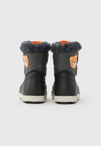 Ein Paar schwarze und graue Winterstiefel für Kinder mit flauschigen Bündchen, orangefarbener Innenauskleidung und lächelnden Tigergesicht-Patches auf der Rückseite.