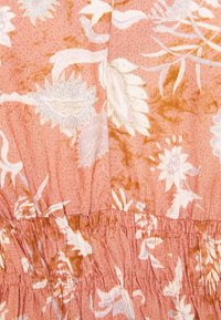 Vestido de tecido floral em pêssego suave com padrões florais brancos e Castanhos. Apresenta detalhe de cintura franzida e um fundo texturizado subtil.