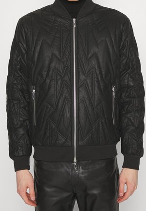 Giubbotto bomber nero con un motivo a zigzag trapuntato, chiusura frontale con zip, tasche laterali e polsi a coste. Realizzato in tessuto Texturizzato con una finitura liscia.