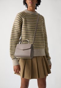 Grå læder håndtaske med en guld-tone håndtag, med en frontklap lukning, parret med en stribet sweater og en plisseret beige nederdel.