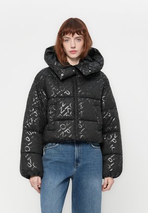 Giacca a vento corta nera con finitura lucida e decorata, cappuccio oversized e chiusura con zip. Presenta maniche voluminosi e tasche frontali.
