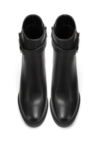 Stivali alla caviglia in pelle nera con una finitura liscia, dotati di cerniera laterale e una fascia regolabile con fibbia metallica. Design a punta arrotondata.