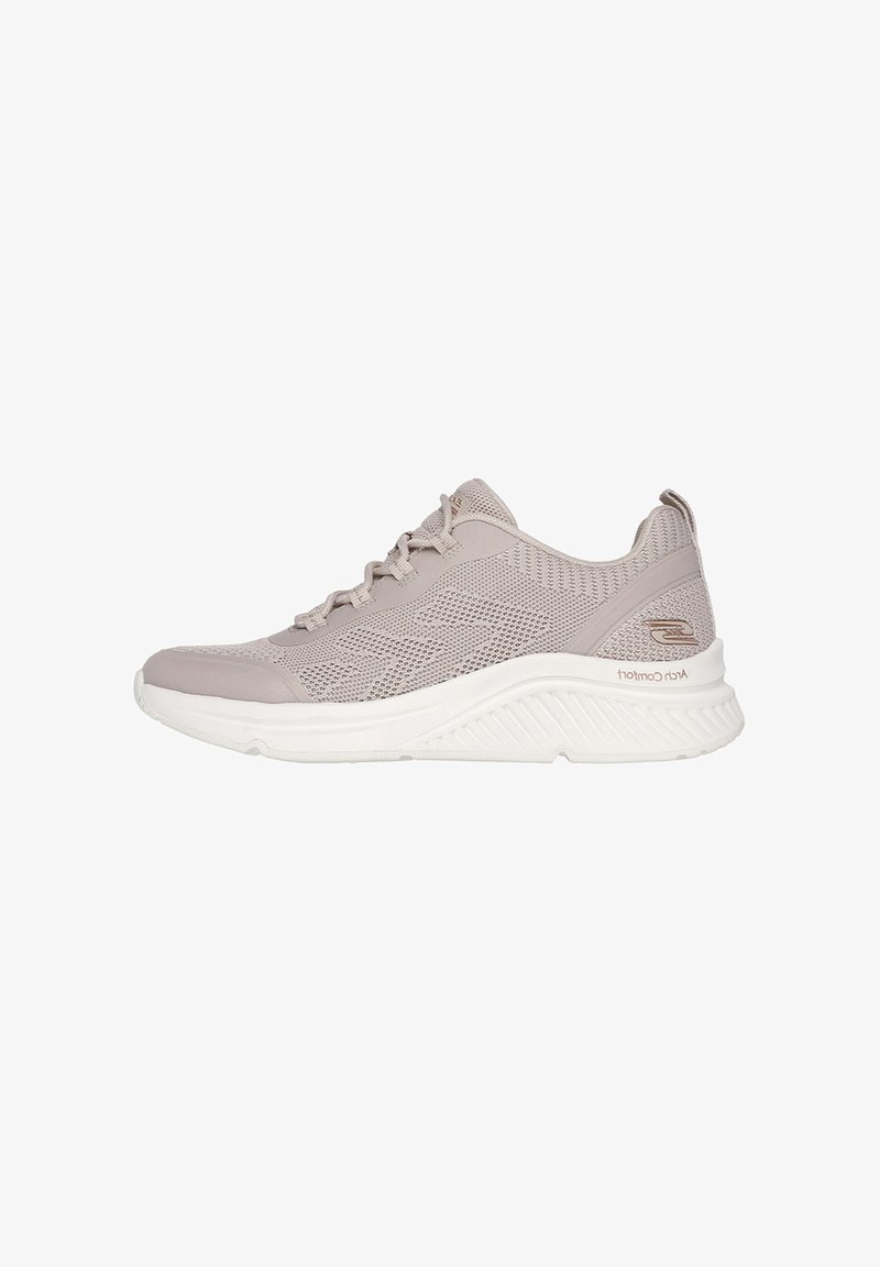 Zapatilla deportiva de color gris claro, hecha de material de punto, con una puntera lisa y suela blanca. Presenta acentos texturizados y una etiqueta con la marca en el talón.