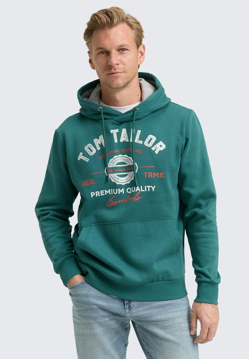 Sudadera con capucha color verde azulado con bolsillo delantero, que presenta texto en blanco y rojo. Tejido suave con un ajuste casual, capucha con capas y puños de canalé.